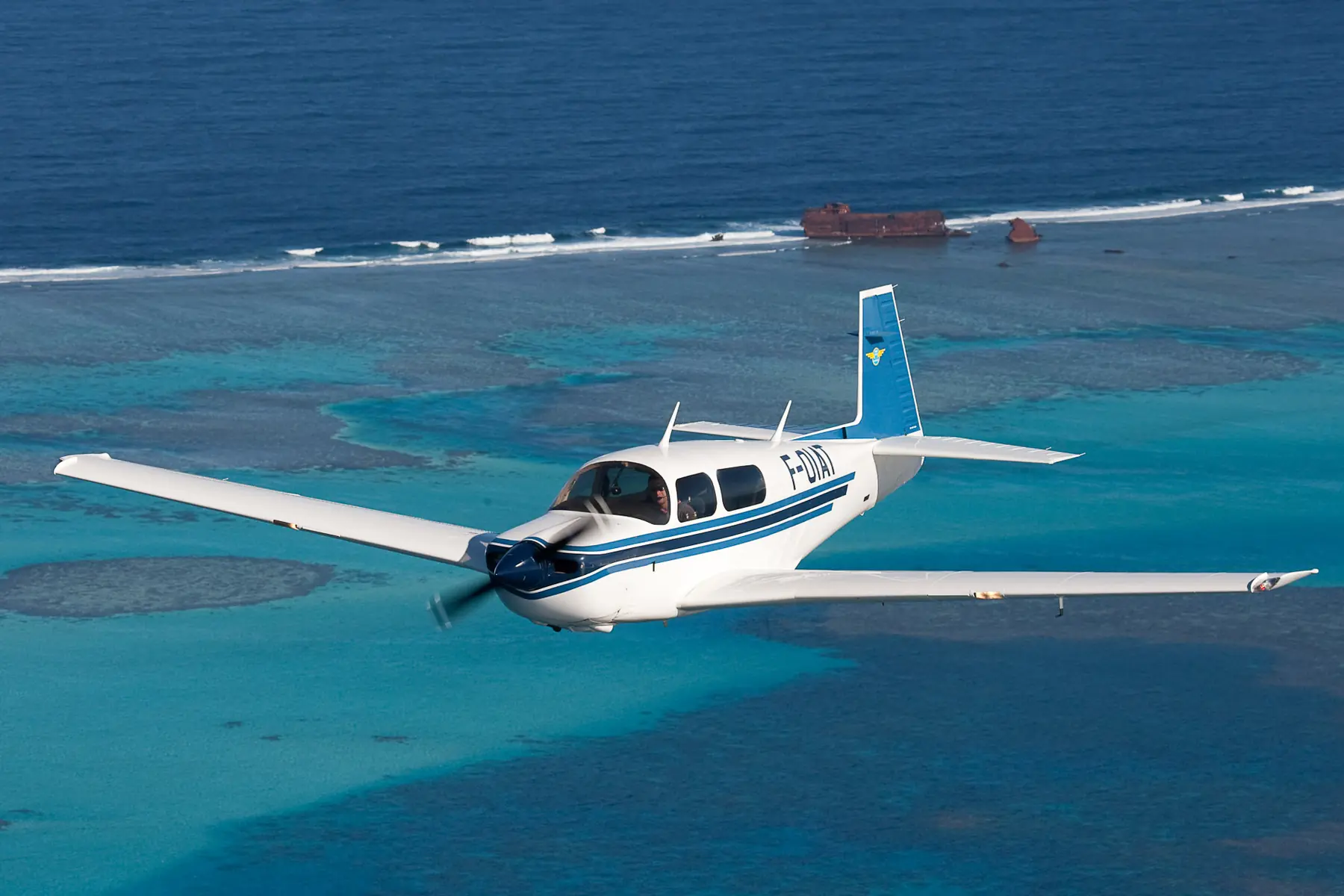 Avion en vol au-dessus du récif corallien et d'une épave échouée