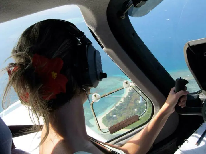 Passagère portant un hibiscus dans les cheveux à bord d'un avion au-dessus d'un îlot